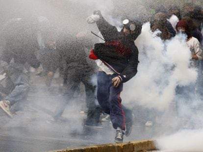Un manifestante lanza una piedra a la policía entre gases lacrimógenos en Santiago.