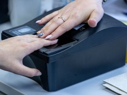 Una mujer captura sus huellas dactilares en un escáner.