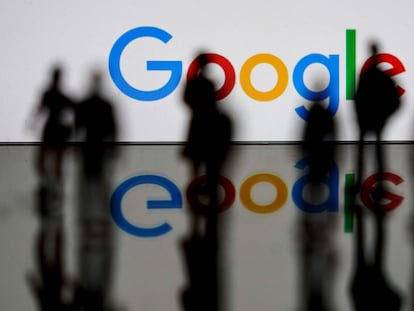Varias personas pasan junto a un logo luminoso de Google.