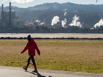 Una mujer pasea este martes frente a la fábrica de celulosa Ence, en Pontevedra.