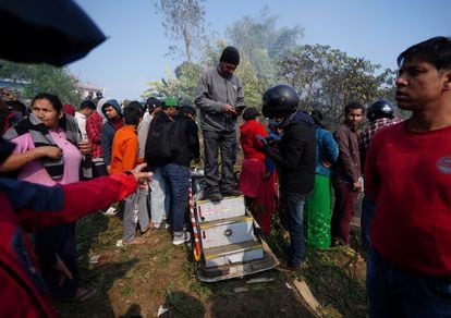 Un hombre subido a los restos de la escalerilla del avión siniestrado en Pokhara, este domingo. 