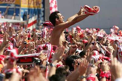 Un seguidor del Sevilla se eleva sobre sus compañeros para dirigir los cánticos.