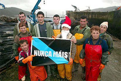 Vecinos de Domaio (ría de Vigo), en el puerto junto a un cartel de Nunca Máis.