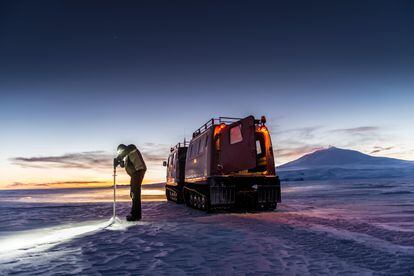 Un hombre del Programa Antártico de los Estados Unidos mide el espesor del hielo marino en el estrecho McMurdo durante el invierno antártico.

