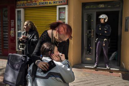 Un agente de policía hace guardia en el portal de un bloque de viviendas durante el desahucio de María Luis Montiel, de 47 años, que llora en el exterior de su vivienda en Madrid (España) tras ser desalojada.