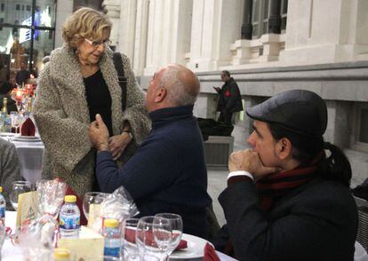 La alcaldesa de Madrid conversa con uno de los 'sin techo' que cenaron esta Nochebuena en la sede del Ayuntamiento.