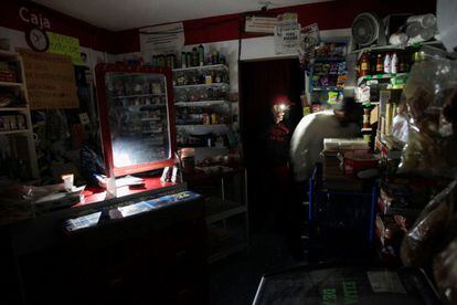 Un cliente es auxiliado por el empleado de una tienda con la luz de su celular en la ciudad de Monterrey, Nuevo León.