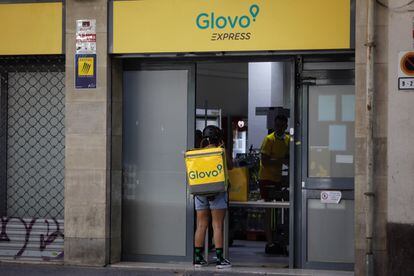 Un rider de Glovo frente a un supermercado express de la compañía de reparto a domicilio en Barcelona.