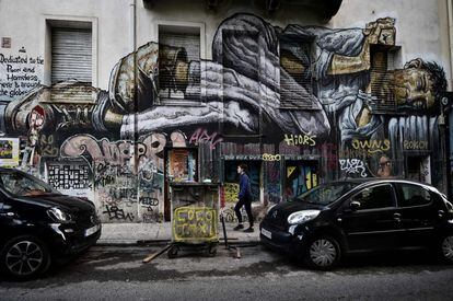 Una mujer pasea frente a un graffiti del artista WD en Atenas.