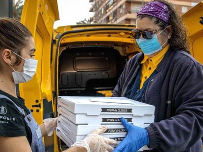 La empleada de la pizzería Del Poble Itziar Úbeda, entrega a una voluntaria de Correos las pizzas realizadas para Food4heroes