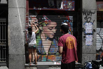 Dos artistas pintan un grafiti en Malasaña.