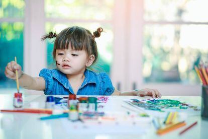 Una niña pinta en casa. 