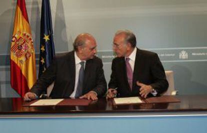 El ministro del Interior, Jorge Fernández Díaz, y el presidente de La Caixa, Isidro Fainé, durante la firma del acuerdo.