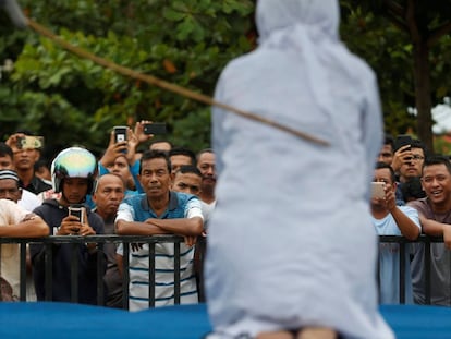 Una multitud de hombres se rien y graban con sus teléfonos móviles como una mujer recibe latigazos en público, acusada de mantener relaciones sexuales fuera del matrimonio en Banda Aceh (Indonesia).