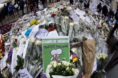 Una copia de la última edición del 'Charlie Hebdo' entre los tributos florales que rodean en París las oficinas de la publicación.