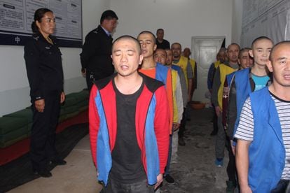 Un grupo de reclusos del centro de reeducación de Tekes, en Xinjiang, vigilados por varios agentes, en septiembre de 2017.