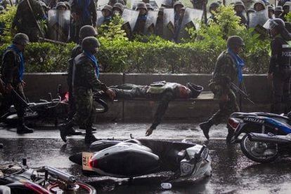 Unos militares transportan el cuerpo del compañero muerto en los enfrentamientos de ayer en las afueras de Bangkok.
