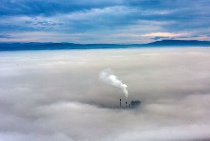 El humo de una fábrica se eleva sobre una espesa capa de niebla y contaminación en Skopje, Macedonia.