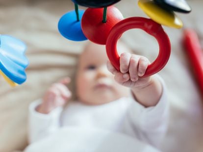 Un bebé juega en su cuna.