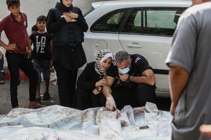 Una mujer y un hombre lloran junto a los cuerpos de víctimas palestinas fallecidas durante los ataques israelíes, frente a la morgue del hospital al-Shifa en la ciudad de Gaza.