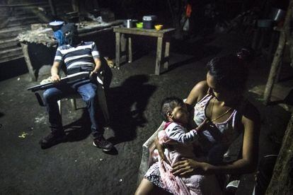 Una madre cuida de su hija mientras que un miembro de los autodefensa descansa después de un patrullaje a altas horas de la madrugada contra la pandilla MS. Dentro de esta guerra, la población civil es siempre la más afectada. Estos grupos son una nueva forma de combatir la violencia. No hay muchos, y todavía trabajan encubiertos, ya que saben que están tomando acciones ilegales, sin embargo, uno accedió a hablar durante la realización de este reportaje. Sus miembros sostienen que el gobierno no está haciendo lo necesario para erradicar todos los asesinatos causados por la pandillas.