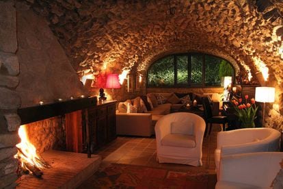 La chimenea abierta destaca como epicentro cálido del gran salón de <a href="http://www.elracodemadremanya.com/" target="_blank">El Racó de Madremanya</a>, masía reconvertida en pequeño hotel de 14 habitaciones en Madremanya, pueblo medieval construido en piedra en la comarca del Gironés, en el límite con el Ampurdán (Girona). La piedra rodea precisamente esta chimenea, tanto en las paredes como en el techo abovedado, creando un ambiente perfecto para una tarde de lectura. La masía también cuenta con chimeneas en algunas de sus habitaciones, piscina climatizada y ofrece servicio de masajes y tratamientos faciales y corporales. Para público adulto. elracodemadremanya.com
