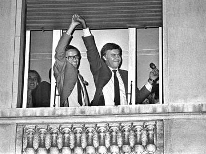 Alfonso Guerra levanta la mano de Felipe Gonz&aacute;lez, asomados a una ventana del hotel Palace, tras conocerse la victoria socialista en 1982.