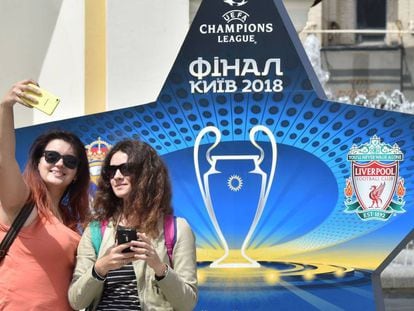 Dos mujeres se fotografían ante un logo de la final de Kiev.