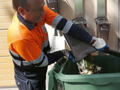 Un operario vierte la basura orgánica de los cubos a un contenedor.