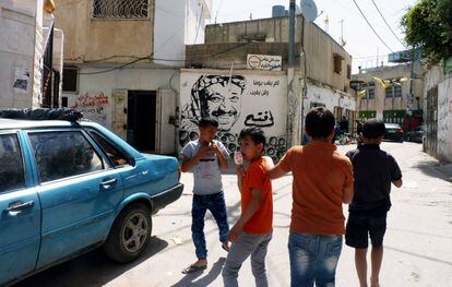 Niños pasean por el campo de reugiados con la imagen de Yasir Arafat en una pintada al fondo.