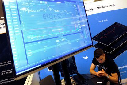 Un hombre junto a una pantalla con la cotización del bitcoin en 2018 en una conferencia en Nueva York sobre blockchain.