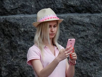 A journalist uses her iPhone as she waits for a news conference in front of the Presidential Administration headquarters in Kiev