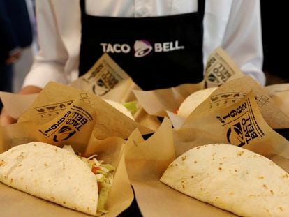 Un empleado de Taco Bell muestra una bandeja llena de tacos.
