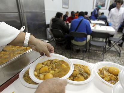 Voluntarios del comedor Cuatro Caminos, en Madrid, sirven comidas.