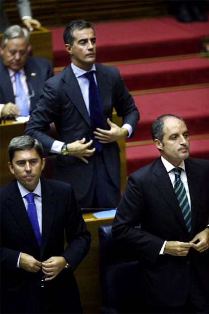 El presidente de la Generalitat Valenciana, Francisco Camps, (a la derecha), el vicepresidente, Vicente Rambla, (izquierda) y el portavoz del grupo popular en las Cortes, Ricardo Costa, se levantan al inicio del pleno de sesión de control en las Cortes Valencianas el 30 de septiembre de 2009.