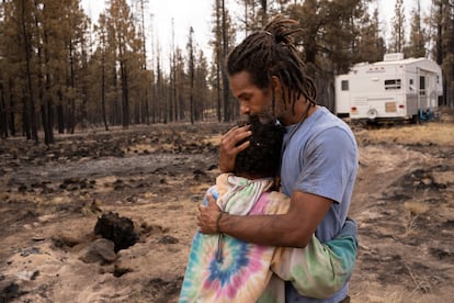Un padre y su hijo se abrazan cerca de una caravana donada después de que su casa se quemara en el Bootleg Fire cerca de Beatty, Oregon, el 19 de julio.