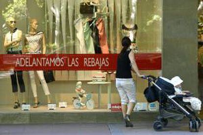 Una mujer observa un escaparate de un establecimiento de Valladolid donde han comenzado las rebajas. EFE/Archivo