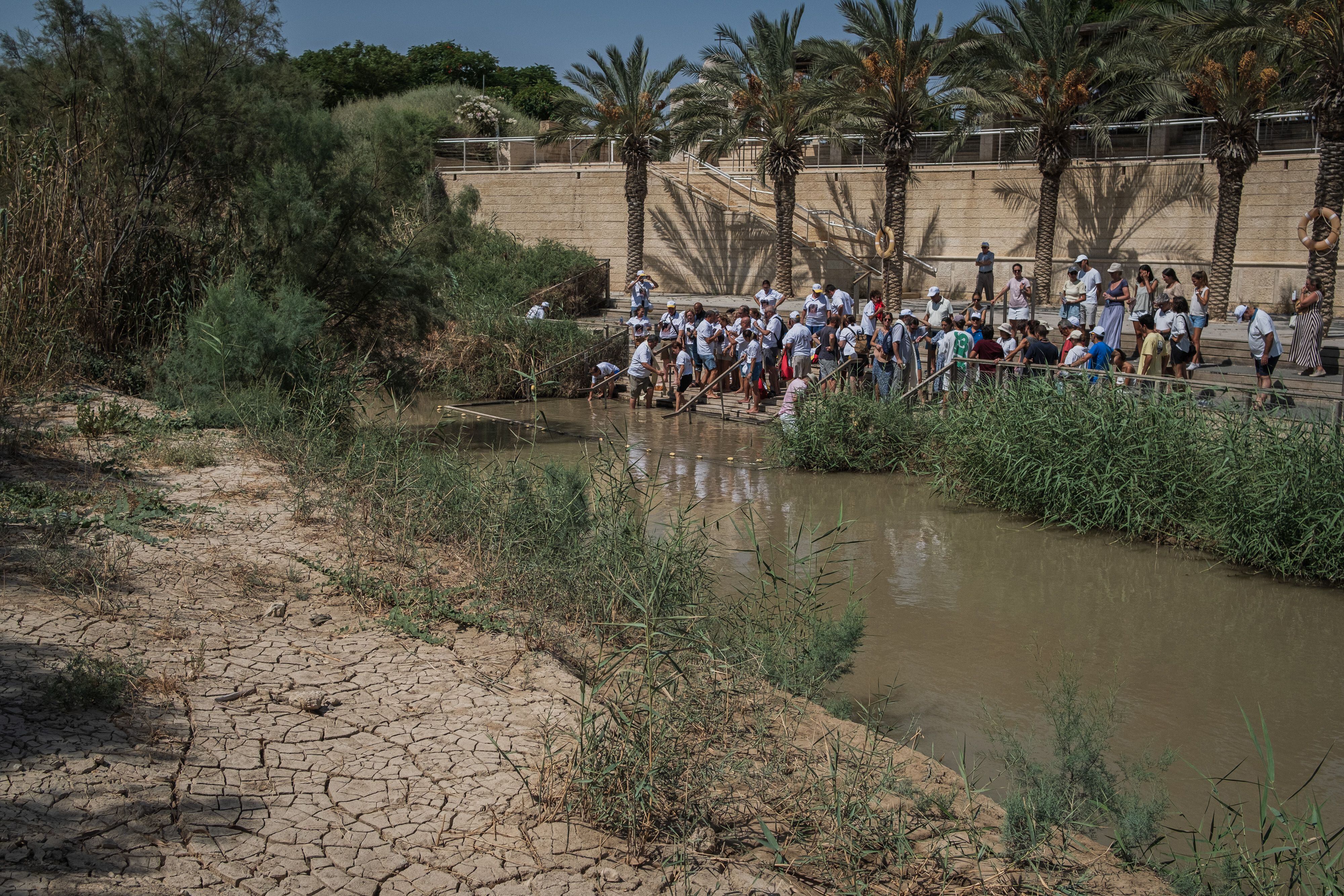 Un grupo de peregrinos se prepara para su bautizo en la parte oriental del río, en Cisjordania. La otra orilla está completamente seca.