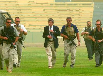 Guardaespaldas privados protegen al antiguo <i>virrey</b> de EE UU Paul Bremer (centro) a la llegada de éste al estadio de Bagdad para felicitar a los futbolistas por su clasificación para los Juegos de Atenas, en junio de 2004.