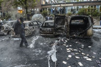 Un hombre camina junto a una hilera de coches carbonizados tras
los disturbios del jueves, en un suburbio de Estocolmo.