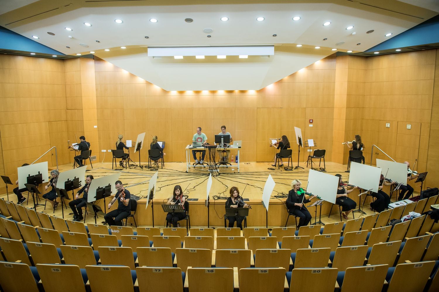 La disposición de todos los violinistas que o bien se dan la espalda o bien les separa una pantalla blanca. En el fondo, Fridman y su compañero controlan la llegada de sonido a los auriculares de los participantes.