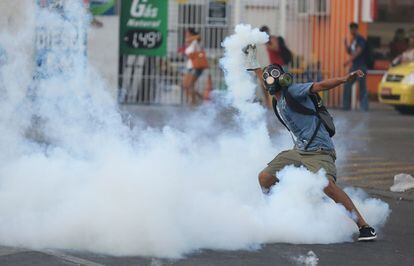 Un manifestante lanza una granada de gas lacrimógeno a la policía durante las protestas contra la subida del precio del transporte público en Brasil.