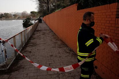 Un bombero acordona una zona mientras algunos de sus compañeros trabajan para retirar un árbol caído en la Casa de Campo.