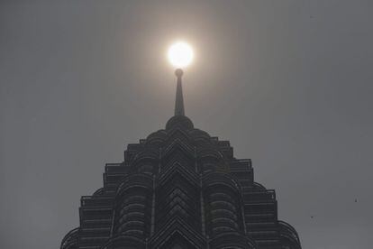 El sol asoma entre la neblina sobre una de las Torres Petronas de Kuala Lumpur (Malasia). Una nube tóxica cubre la zona del sudeste asiático entre las islas de Sumatra, Borneo e Indonesia, provocada por la acumulación de CO2 en el ambiente. Al menos 200 incendios que se encuentran activos en la zona.