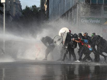 Manifestantes son reprimidos con agua a presión durante una protesta contra el Gobierno de Chile en Santiago el 20 de noviembre.