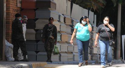 Dos mujeres pasan al lado de decenas de ata&uacute;des apilados fuera del Instituto de Medicina forense de Comayagua (Honduras). 