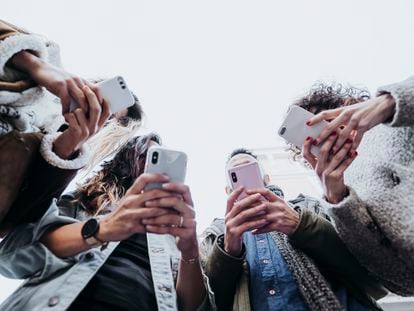 Cuatro amigos usan sus teléfonos móviles en la calle.