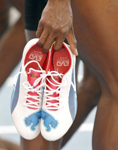Bolt con sus zapatillas en las manos.