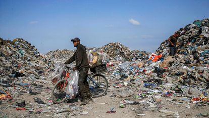 Un recolector de basura palestino empuja una bicicleta cargada con latas de aluminio y otros desechos en un vertedero en la ciudad de Gaza, el 29 de julio de 2019. Algunos palestinos, impulsados por la pobreza exacerbada y la falta de oportunidades de empleo, han recurrido a peinar los vertederos, para vender trozos de basura y chatarra.