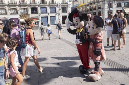 Minnie y Mickey con unos turistas que se van a fotografiar con ellos a cambio de dinero en la puerta del sol este jueves.